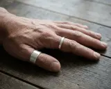Mano maschile con due anelli d'argento, uno al pollice, che evoca un senso di stile e un possibile anello al pollice significato.
