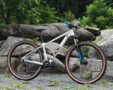 Biały rower Cube z brązowymi oponami, idealny jako rower na długie trasy. Wyposażony w amortyzator RockShox i napęd Shimano.