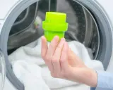 Grüne Kappe mit Waschmittel wird in die Waschmaschine gegeben.