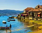 Un pueblo costero gallego, con barcas en el agua y casas de piedra, uno de los pueblos mas bonitos de Galicia.