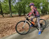 Dziewczynka na rowerze, idealny rozmiar roweru dla 10 latka. Jesienny park, liście na ziemi.
