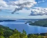Vacker utsikt över en sjö med öar, omgiven av skogklädda berg. Ett perfekt ställe att uppleva Stockholms naturreservat.