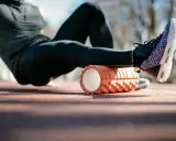 Sportler nutzt eine Faszienrolle vor oder nach dem Training zur Regeneration der Beinmuskulatur.