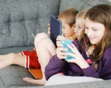 Trois enfants absorbés par leurs écrans, un rappel pour un atelier sensibilisation aux écrans.