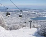 Funivia su montagne innevate, un lago azzurro sullo sfondo. Scopri dove sciare in Calabria per un'esperienza indimenticabile.