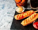 Pyszny corn dog przepis na patyku, podany z ketchupem i musztardą. Idealna przekąska!