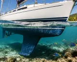Vue sous-marine d'un voilier de 6m, avec sa quille et son hélice. Le prix antifouling bateau 6m est une préoccupation pour maintenir cette coque propre. Poissons et coraux dans les eaux claires.
