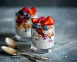 Två glas med chiapudding, toppade med bär och granola. Ett perfekt chiapudding recept för en hälsosam frukost eller mellanmål.