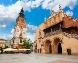 Wieża ratuszowa Kraków na Rynku Głównym, obok Sukiennic. Słoneczny dzień, błękitne niebo z chmurami.