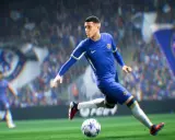Piłkarz w niebieskiej koszulce Chelsea drybluje piłką na boisku, gotowy do strzału w grze FIFA 2k.