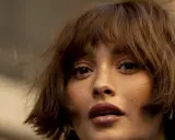 Nahaufnahme einer Frau mit einer lässigen, braunen Hipster-Frisur und einem nachdenklichen Blick.