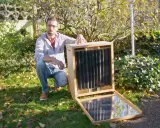 Un homme présente un séchoir solaire plan, un appareil ingénieux pour sécher des aliments grâce à l'énergie du soleil.