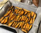 Patate dolci al forno tagliate a spicchi, condite con rosmarino e spezie, pronte per essere gustate.