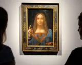 Two viewers admire Leonardo da Vinci's "Salvator Mundi," the most expensive piece of art ever sold, in its ornate frame.