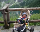 Niemowlak w wózku podziwia Tatry. Piękny widok na jezioro i góry.