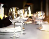 Verres à vin vides sur une table dressée, prêts pour un repas. L'emplacement verre table est soigné, reflétant la lumière ambiante.