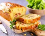 Tranche de cake jambon fromage dorée, garnie d'herbes fraîches, prête à être dégustée.