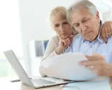 Zmartwieni seniorzy analizują dokumenty, szukając informacji, komu przysługuje emerytura pomostowa.