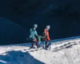 Dwóch alpinistów z raki i czekanami na lodowcu, przygotowuje się do wspinaczki.