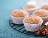 Leckere Apfelmus Muffins mit Zimt bestreut auf einem Gitter, daneben Zimtstangen.
