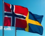 Flaga Norwegii i Szwecji powiewają na tle błękitnego nieba.