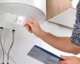 Técnico ajusta el control de temperatura de un termo eléctrico que no enciende.