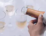 Eine Hand gießt Champagner in ein Glas. Die Bläschen steigen auf und lassen erahnen, wie gut der Champagner schmeckt.