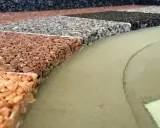 Przykładowe wykończenie tarasu betonowego: próbki nawierzchni z kamienia naturalnego w różnych kolorach, obok zielonej, gładkiej powierzchni.