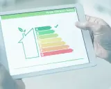 Persona revisa en tablet la validez del certificado energético de una casa, mostrando una escala de eficiencia.