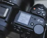 Górna część aparatu Nikon Z6 III z widocznym ekranem LCD, pokrętłem trybów i przyciskiem nagrywania.