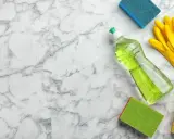 Reinigungsutensilien wie Spülmittel, Handschuhe und Schwämme liegen bereit, um Marmor zu reinigen.