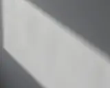Światło podkreśla nierówności na elewacji, tworząc cień o geometrycznym kształcie.
