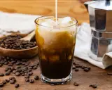Ein Glas Eiskaffee mit Milch, Eiswürfeln und Kaffeebohnen. Perfekt für dein Cold Brew Rezept.