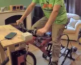 Un homme pédale sur un vélo d'appartement pour produire de l'électricité, chargeant son téléphone.