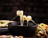 Fondue au fromage, une des spécialités culinaires parisiennes, servie avec du pain et des raisins.