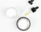Dwa słoiczki kremu i pipetki z serum, idealne do pielęgnacji skóry głowy z kwasem salicylowym.