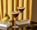 Zwei elegante Gläser mit cremigem Espresso-Martini-Look, garniert mit Kaffeebohnen. Ein alkoholfreier Genuss, der Luxus ausstrahlt.