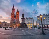 Rynek Główny w Krakowie o zachodzie słońca. Bazylika Mariacka i pomnik Mickiewicza. Ciekawe informacje o Krakowie znajdziesz w tym miejscu.