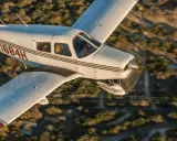 Eine Piper Cherokee 140 fliegt über eine bewaldete Landschaft.