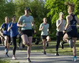 En grupp kvinnor tränar löpning i en park, redo att springa 3 km.