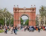 Łuk Triumfalny w Barcelonie, jeden z punktów z listy barcelona top 10, otoczony palmami i tłumem turystów.