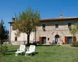 Un casale in pietra con giardino e lettini, perfetto per vacanze tranquille ad agosto in Italia.