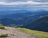 Kamienista ścieżka prowadzi przez zielone zbocza w kierunku malowniczych gór Mała Fatra.