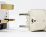 Reiseadapter für den Strom in Spanien. Ein britischer Stecker trifft auf einen europäischen Stecker.