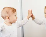 Bambino che tocca il suo riflesso, un momento chiave nella costruzione del sé nel bambino.