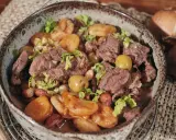 Un savoureux tajine de chevreuil mijoté avec des pommes de terre et des olives, garni de coriandre fraîche.