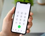 Dłoń trzyma smartfon z klawiaturą numeryczną. Chcesz wiedzieć, jak sprawdzić numer? Wpisz go na klawiaturze telefonu.