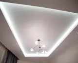 Nowoczesny sufit napinany lustrzany z podświetleniem LED i designerską lampą.