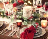 Tavola apparecchiata per un magico pranzo di Natale, con candele, pigne e luci scintillanti. Dove andare per un'atmosfera così?