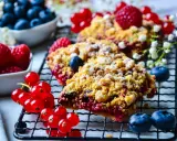 Délicieux crumble aux fruits rouges, garni de framboises, myrtilles et groseilles, saupoudré de sucre glace.